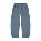 A pair of slate blue athletic jogger pants with an elastic waistband and a small white logo on the left thigh, shown against a plain white background.
