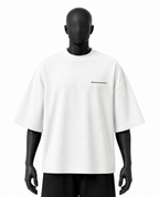 A white oversized short-sleeve t-shirt with a small black 'REALITY' logo on the left chest, displayed on a matte black mannequin against a plain white background.