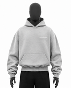 A light gray pullover hoodie displayed on a black mannequin torso, featuring a kangaroo pocket and a small white embroidered logo on the left chest, set against a plain white background.