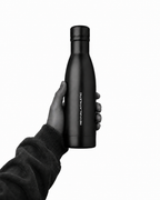 A hand holding a matte black Revival Bottle against a solid white background.